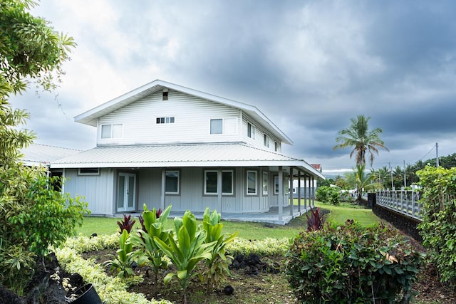 rear view of property featuring a porch, metal roof, a yard, and fence