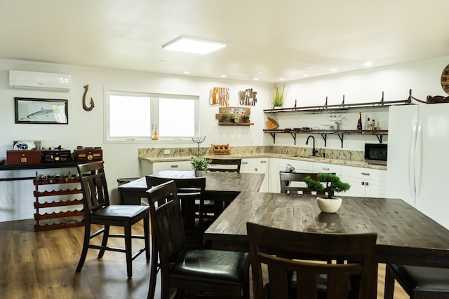 kitchen with dark hardwood / wood-style floors, white refrigerator, white cabinetry, sink, and a wall mounted air conditioner