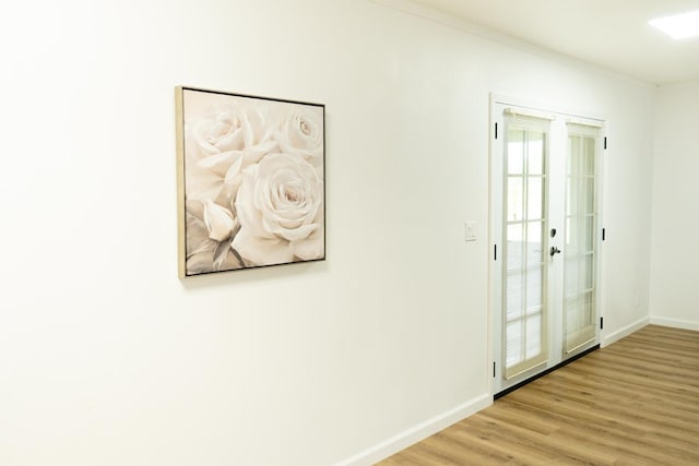 hallway featuring light wood finished floors, baseboards, and crown molding