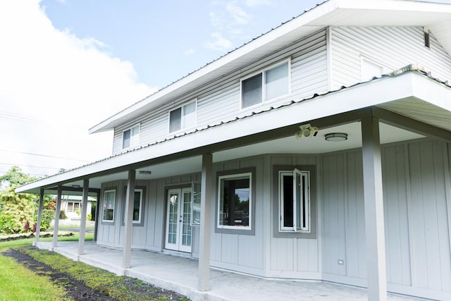 exterior space featuring metal roof, board and batten siding, and french doors