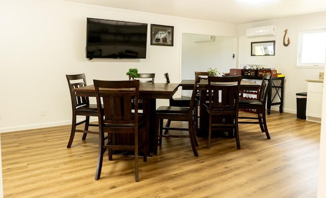 dining area with an AC wall unit, light wood finished floors, and baseboards