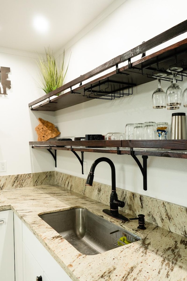 interior details featuring open shelves, light stone counters, a sink, and white cabinets