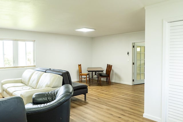 living area featuring crown molding, light wood finished floors, and baseboards