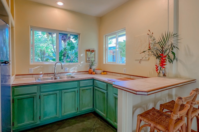 kitchen featuring dark tile patterned flooring, sink, tile countertops, and stainless steel fridge