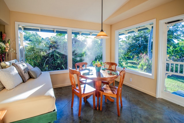 dining room with dark tile patterned flooring and vaulted ceiling