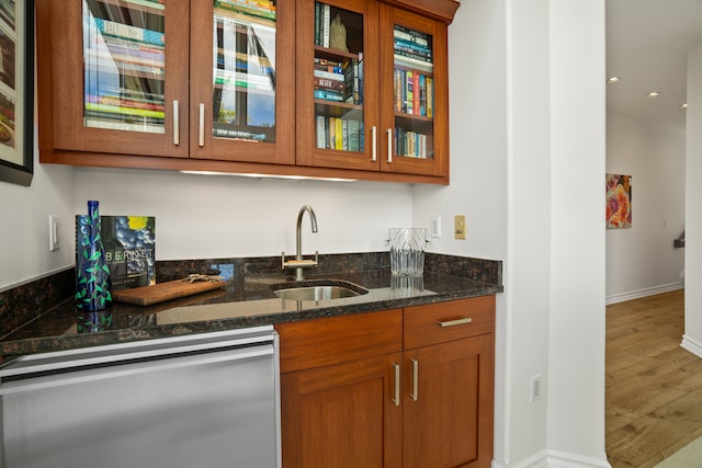 kitchen with sink, dishwasher, dark stone countertops, and hardwood / wood-style flooring