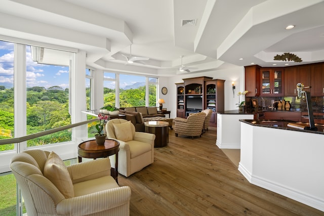 living room featuring ceiling fan, a raised ceiling, and dark hardwood / wood-style flooring