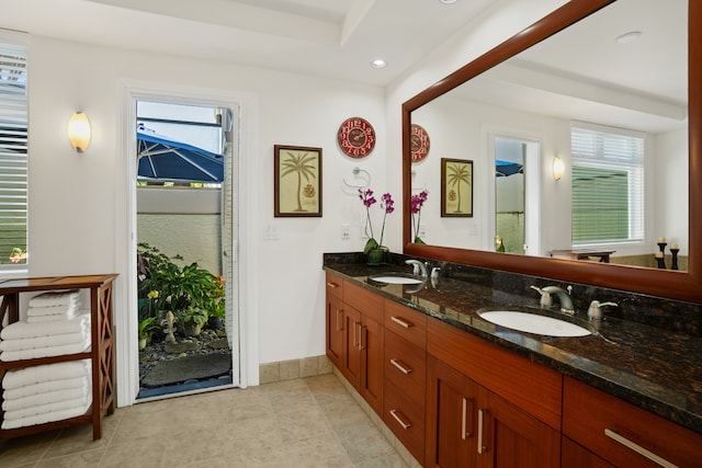 bathroom with double vanity, tile patterned flooring, and a healthy amount of sunlight