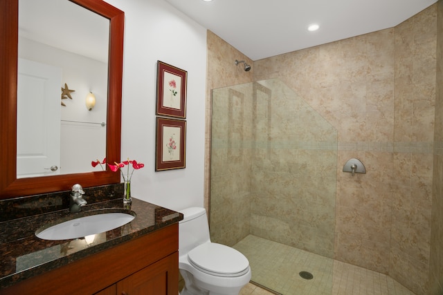 bathroom with tiled shower, vanity, and toilet