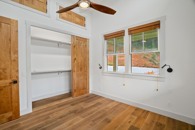 unfurnished bedroom with ceiling fan, a closet, and hardwood / wood-style flooring