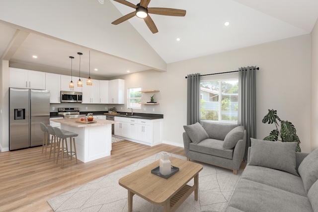 living room with light hardwood / wood-style floors, a wealth of natural light, high vaulted ceiling, and ceiling fan