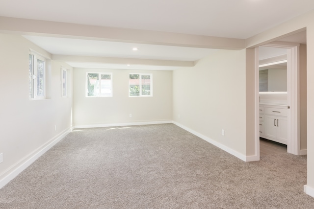 empty room featuring beamed ceiling and light carpet