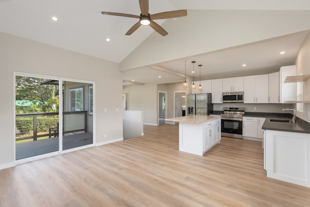 kitchen with appliances with stainless steel finishes, light hardwood / wood-style floors, white cabinetry, high vaulted ceiling, and a center island