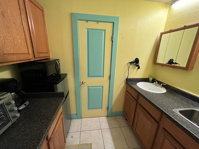 bathroom featuring tile patterned flooring, a sink, and baseboards