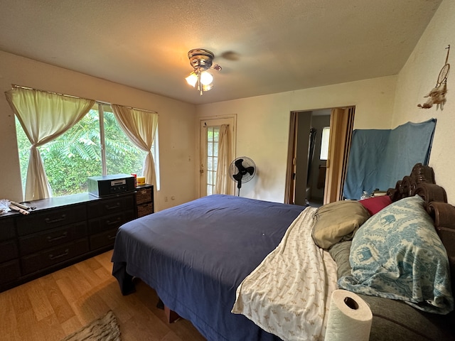 bedroom with a textured ceiling, light hardwood / wood-style floors, and ceiling fan