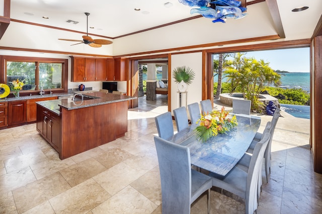 kitchen with dark stone counters, ceiling fan, an island with sink, and plenty of natural light