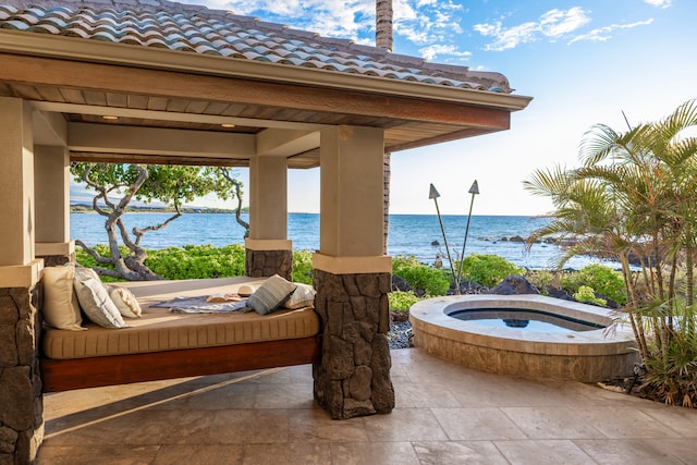 view of patio / terrace with a gazebo, a water view, and an in ground hot tub