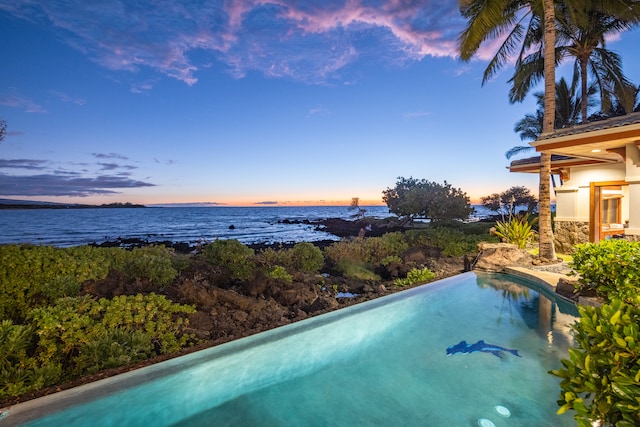 pool at dusk featuring a water view