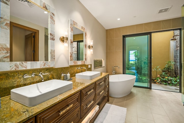 bathroom with vanity, tasteful backsplash, a bathing tub, tile walls, and tile patterned flooring