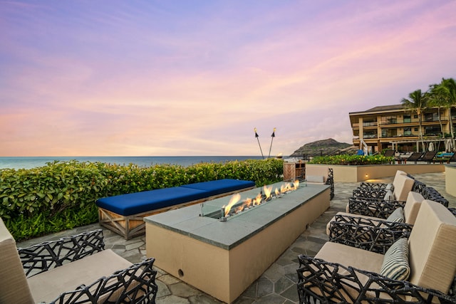 patio terrace at dusk with a water view and a fire pit