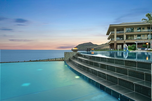 pool at dusk with a water and mountain view