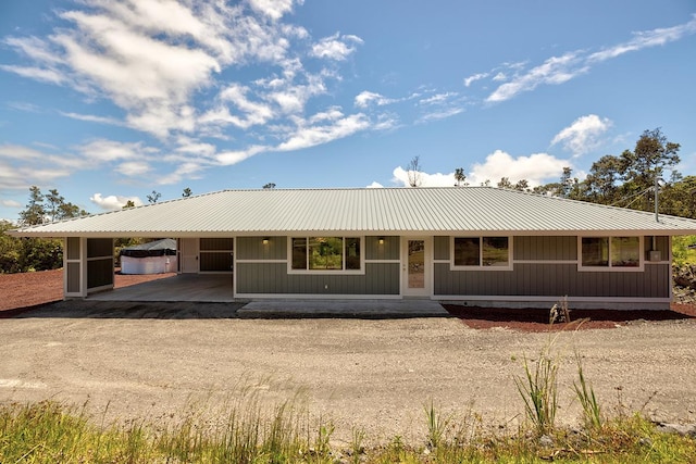 ranch-style home with an attached carport, driveway, and metal roof