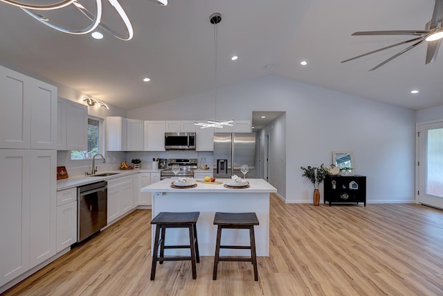 kitchen featuring appliances with stainless steel finishes, a kitchen island, light countertops, and a sink