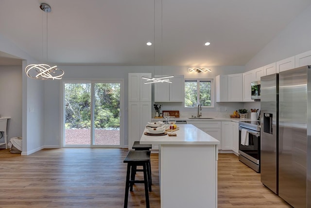 kitchen with a breakfast bar area, a sink, stainless steel appliances, light countertops, and white cabinetry