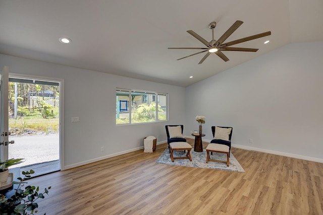 living area featuring vaulted ceiling, light wood-style floors, and a wealth of natural light