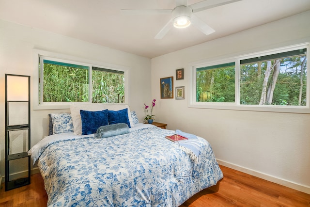 bedroom featuring multiple windows, hardwood / wood-style floors, and ceiling fan