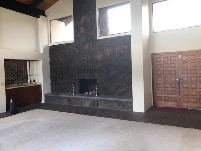 unfurnished living room with carpet flooring, high vaulted ceiling, and french doors