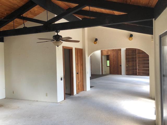 carpeted empty room with arched walkways, ceiling fan, high vaulted ceiling, wood ceiling, and beam ceiling