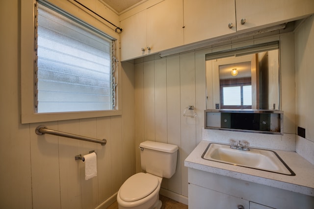 bathroom with wooden walls, toilet, crown molding, and vanity