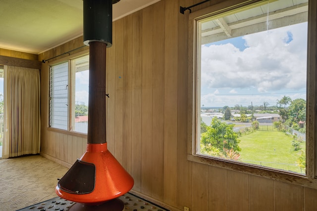 interior space featuring a wealth of natural light, wood walls, and a wood stove