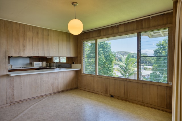 kitchen with wood walls, sink, kitchen peninsula, and pendant lighting