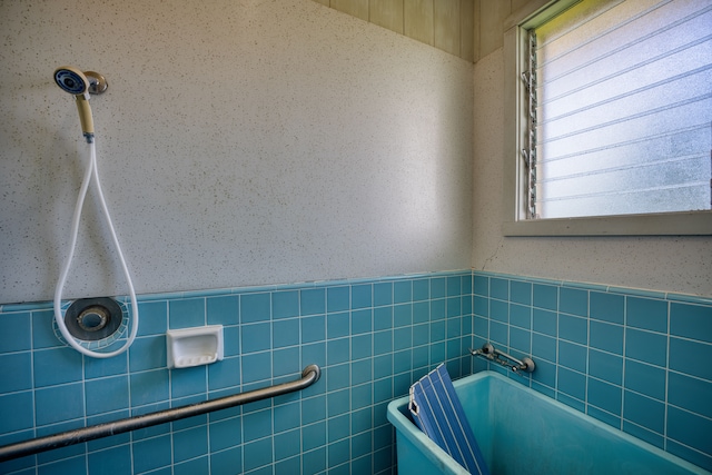 bathroom featuring tile walls, plenty of natural light, and a tub to relax in