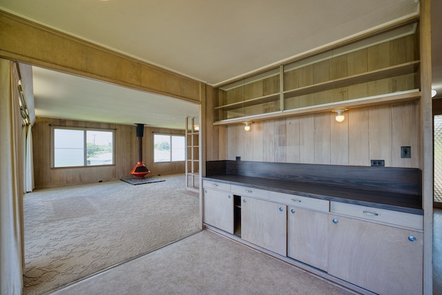 kitchen with light colored carpet, wooden walls, and light brown cabinetry