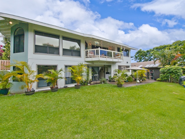 rear view of property featuring a lawn and a balcony