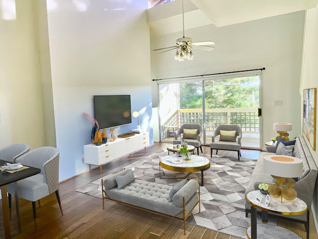 living room featuring ceiling fan, a high ceiling, and wood finished floors