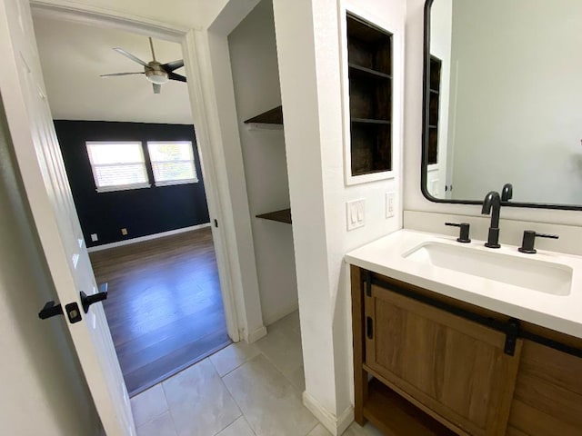 bathroom with built in shelves, a ceiling fan, vanity, baseboards, and tile patterned floors