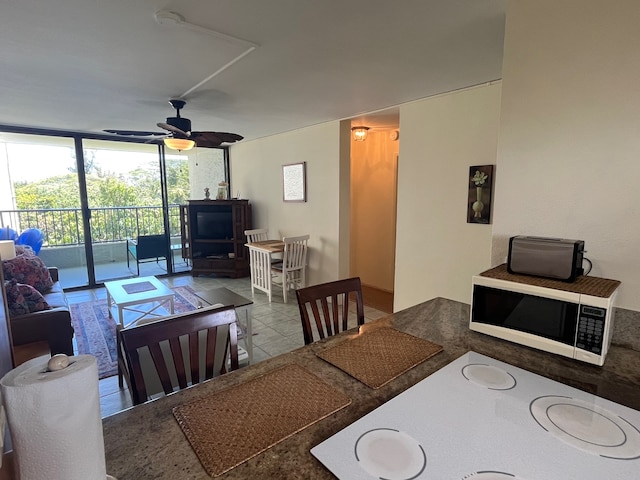 tiled dining area with ceiling fan and expansive windows