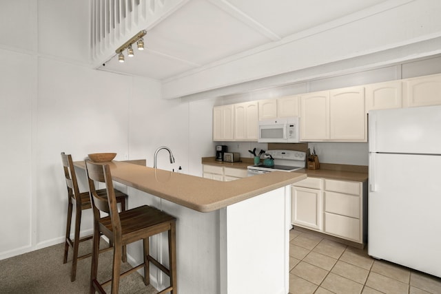 kitchen featuring white appliances, light tile patterned flooring, sink, a breakfast bar, and white cabinets