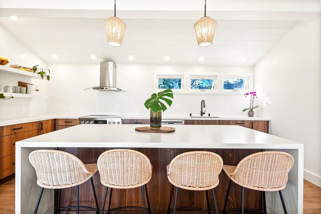 interior space featuring light hardwood / wood-style floors, sink, wall chimney exhaust hood, and a center island