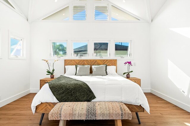 bedroom featuring hardwood / wood-style flooring and high vaulted ceiling