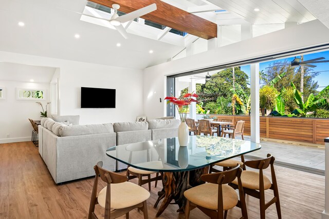 dining room with vaulted ceiling with skylight, ceiling fan, and light hardwood / wood-style floors