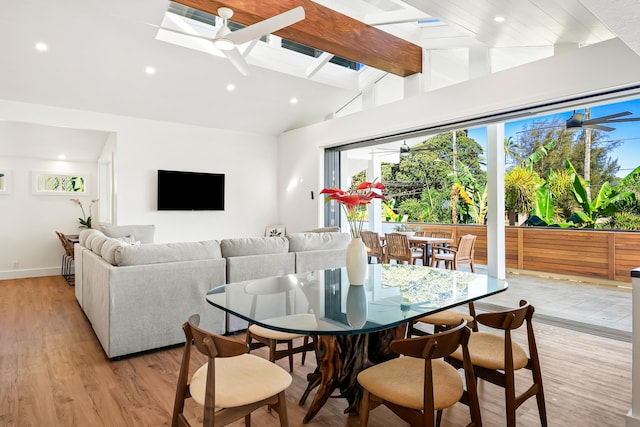 dining room featuring vaulted ceiling with skylight, light wood-style flooring, recessed lighting, a ceiling fan, and baseboards