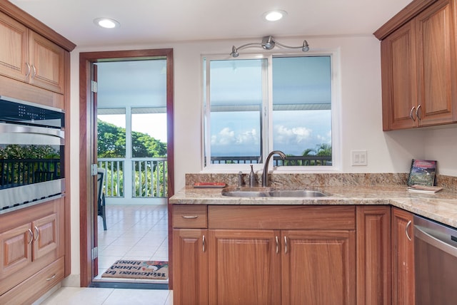 kitchen with light tile patterned flooring, stainless steel appliances, sink, and light stone countertops