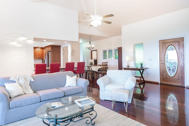 living room with a towering ceiling, ceiling fan with notable chandelier, and dark hardwood / wood-style flooring