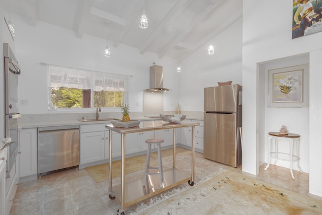 kitchen with wall chimney range hood, beam ceiling, white cabinetry, appliances with stainless steel finishes, and sink