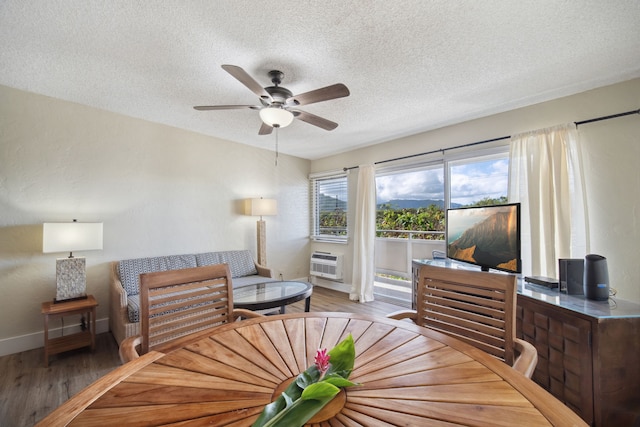 living room featuring ceiling fan, hardwood / wood-style flooring, an AC wall unit, and a textured ceiling